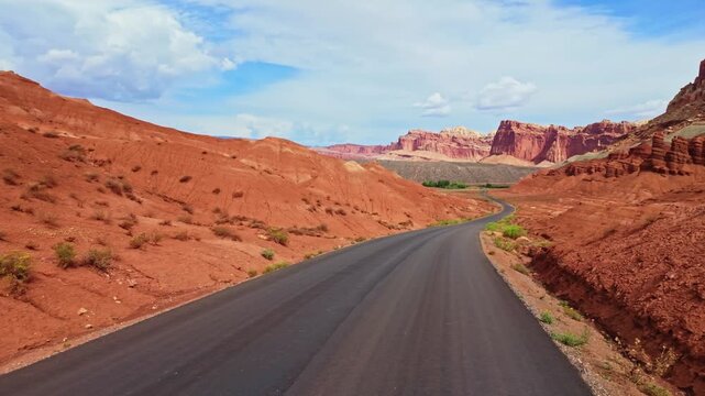 Towering red rock walls and colorful cliffs flank the paved Scenic Drive through the heart of Capitol Reef National Park Utah