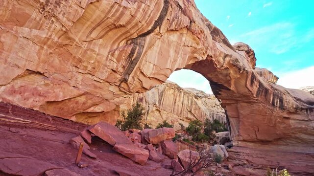 Massive natural sandstone arch spans rugged canyon terrain along Hickman Bridge trail in Capitol Reef National Park Utah