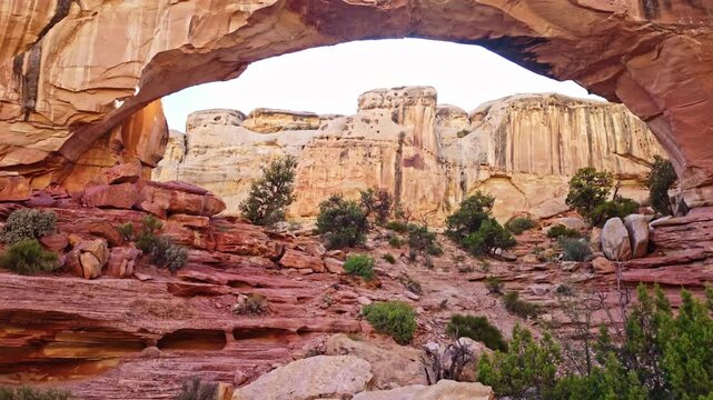 Massive natural sandstone arch spans rugged canyon terrain along Hickman Bridge trail in Capitol Reef National Park Utah