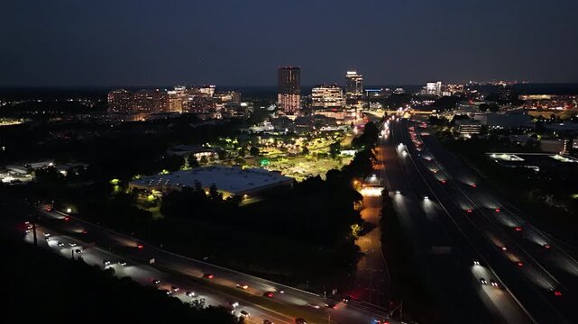 Aerial drone hyperlapse of illuminated city skyline and highway traffic at night in Reston, Northern Virginia, showcasing urban infrastructure, commercial real estate, and regional transit.