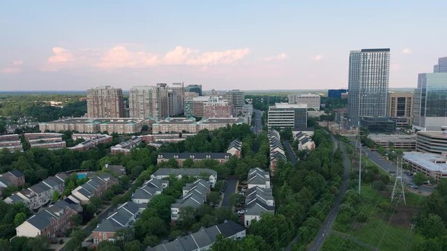 Aerial drone view of modern high-rise skyline, residential townhomes, and green canopy in Reston and Herndon, Northern Virginia, highlighting suburban development and real estate.