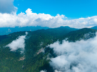 Aerial view of the lush green mountains in Dabie Shan located in Hubei province China with clouds drifting over the scenic landscape during a bright summer day © AS_SleepingPanda
