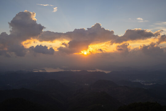The sun sets over the scenic Dabie Mountains landscape in Hubei province China creating a beautiful golden glow above the rolling hills and the distant water surface
