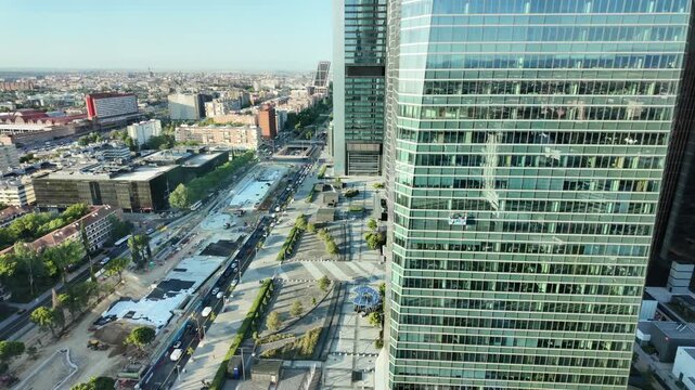 Elevated city view over Madrid's Cuatro Torres business district with glass office buildings, streets and traffic below.