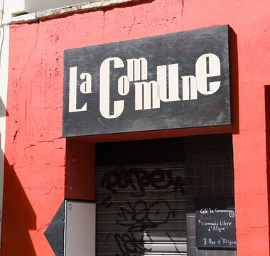 PARIS, FRANCE - SEPTEMBER 1, 2026 - La Commune cafe sign displayed on a vibrant red wall in Aligre, Paris