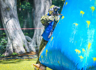 paintball sport player in protective uniform and mask playing with gun outdoors © Maria