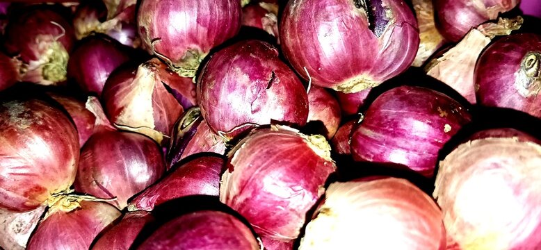 Close-up of fresh red onion bulbs with vibrant purple skins, natural textures and earthy details for food and agriculture concepts
