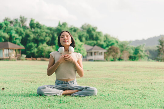 Smiling woman sitting green grass enjoy nature park outdoors, relaxing peaceful summer day while breathing fresh air, feeling happy lifestyle wellbeing health balance mindfulness harmony