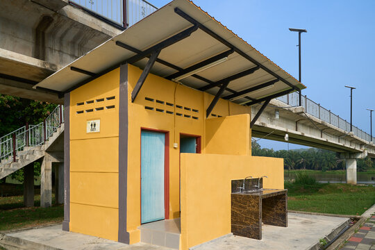 Small yellow toilet or restroom building with a roof near an elevated bridge platform structure platform structure architecture transportation facility elevated concrete stairway