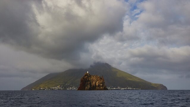 Stromboli island with offshore islet Strombolicchio, clear image of a volcanic island with dramatic clouds and calm coast, UNESCO World Heritage Site, Aeolian Islands, Aeolian Islands, Sicily, Italy