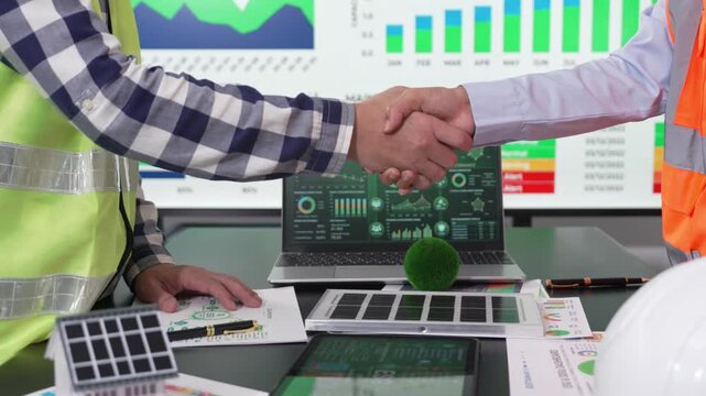 Two engineers shaking hands after successful ESG green energy and solar panel project meeting.