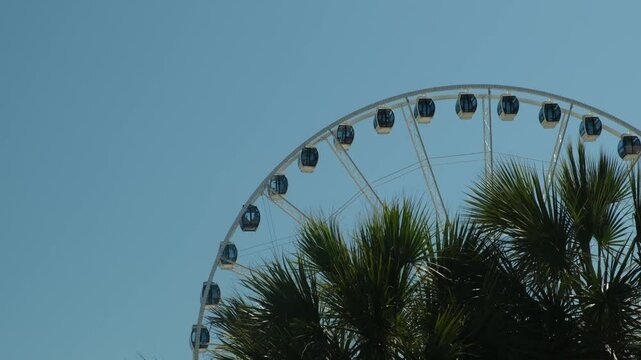 a view of a large Ferris wheel against a blue sky and darkness in the foreground