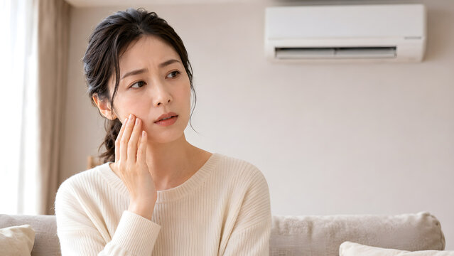 暖房の効いた部屋で頬の乾燥を気にする日本人女性