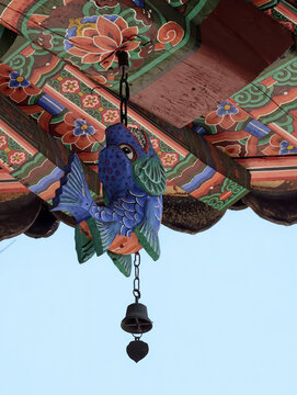Traditional Korean wind chime with wooden fish under decorated temple eaves at Pohyon Temple, North Korea