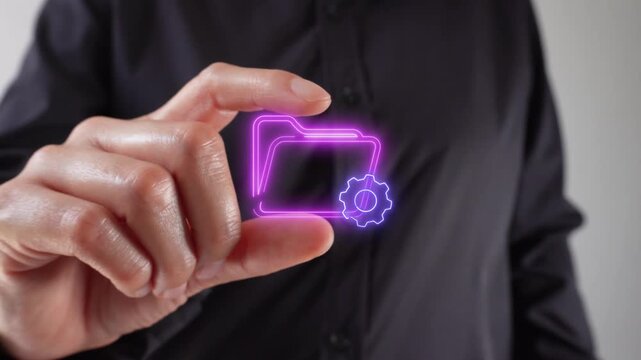 Close-up of a woman's hands holding a virtual icon of a folder with a gear between two fingers.