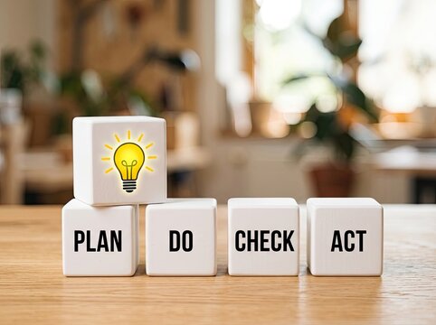 White cubes showing plan do check act with a glowing lightbulb suitable for management presentations symbolizing continuous improvement and innovation
