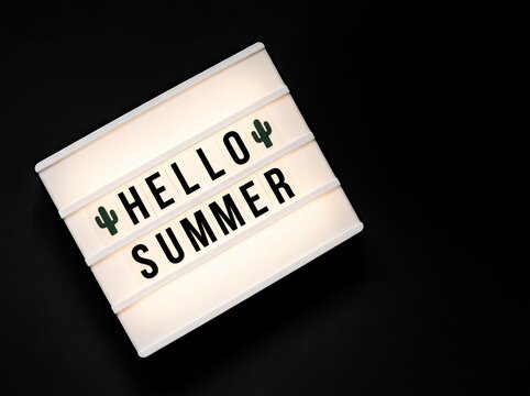 Illuminated lightbox displaying Hello Summer with cactus icons on black background perfect for seasonal promotions symbolizing warmth and vacation