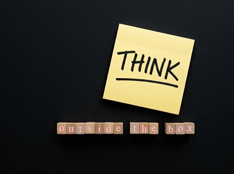 Yellow sticky note with text THINK above wooden blocks spelling outside the box ideal for corporate marketing representing creative solutions
