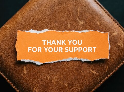 Torn orange paper with text on brown leather surface ideal for business marketing symbolizing gratitude help and customer care