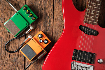 Red Electric Guitar and Two Effects Pedals on Rustic Wooden Background. © poomsak