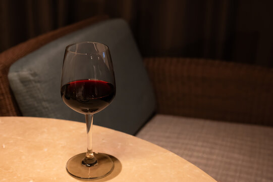 Glass of red wine on a table indoors.