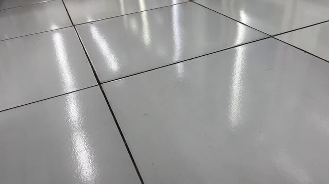 Shiny white ceramic floor tiles texture with bright light reflections