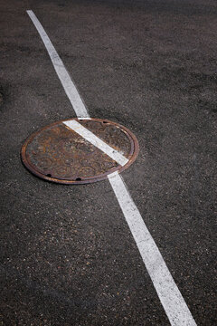 Man Hole Manhole Cover Made of Iron Worn and Rusty with Painted White Line for Street on Aspalt Marking Skewed Position