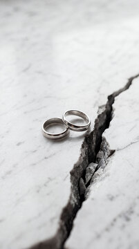 Broken Wedding Rings on Cracked Surface Divorce and Separation Concept