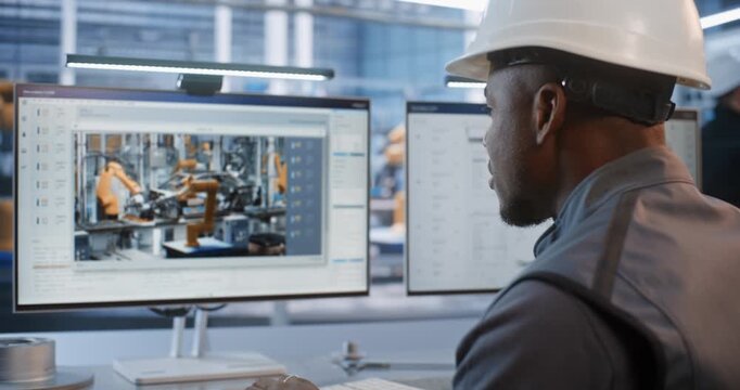 Engineer in Safety Gear Evaluates Automotive Component CAD Graphics on Desktop Computer Monitor. Cyber Physical Technology Drives Efficiency in Smart Heavy Industry Plant Workflows. AI Manufacturing.