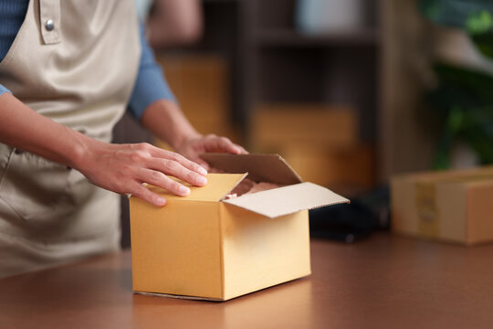 Small business worker packing cardboard box for e-commerce parcel shipping