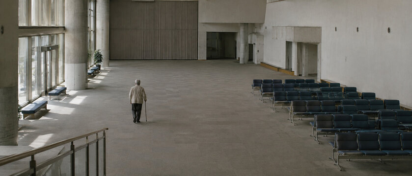 Older Adult Walking Alone Through Empty Community Center