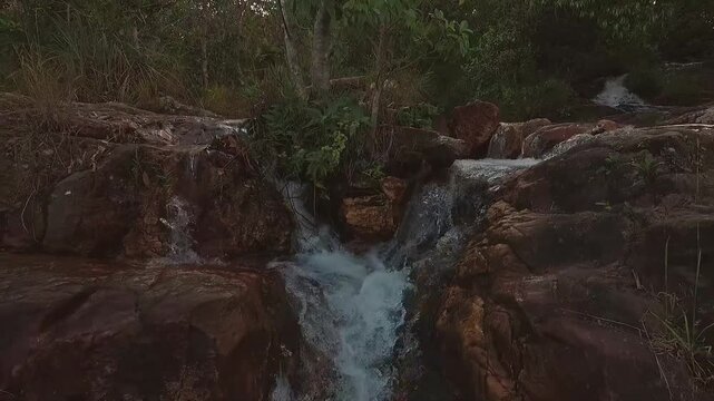 Loquinhas Waterfall rushes over weathered rock in Alto Paraiso de Goias, Goias, Brazil, South America, within Chapada dos Veadeiros, extreme close-up FPV drone pullback.