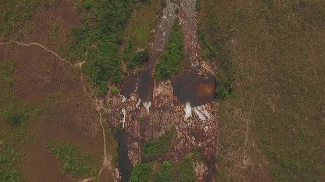 Couros Waterfalls flow through exposed rock in Alto Paraiso de Goias, Goias, Brazil, South America, within Chapada dos Veadeiros, slow top-down drone forward flyover.