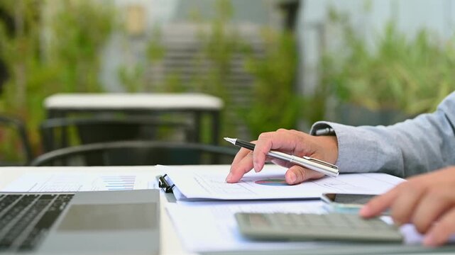 Executive performs financial analysis outdoors, reviewing investment chart metrics, conducting market data analysis beside investment risk document checking as business analysis continues.