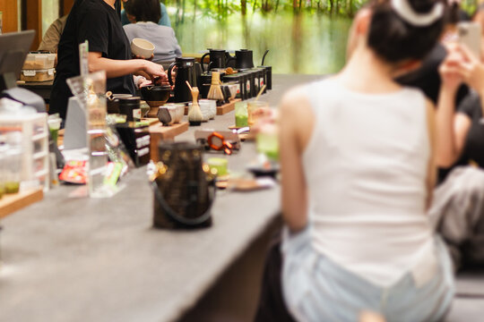 Customers sitting at counter while a barista prepares Japanese matcha green tea .
