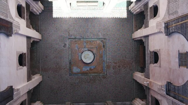 Direct 90-degree overhead drone perspective capturing the symmetrical courtyard, central fountain, and zellige tilework of a historic madrasa in Fez, Morocco.