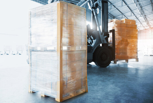 Package Boxes Wrapped Plastic on Pallets in Warehouse. Forklift Loading in Distribution Warehouse. Logistics Warehouse. Package Boxes Supplies. Supply Chain Shipment Goods. 