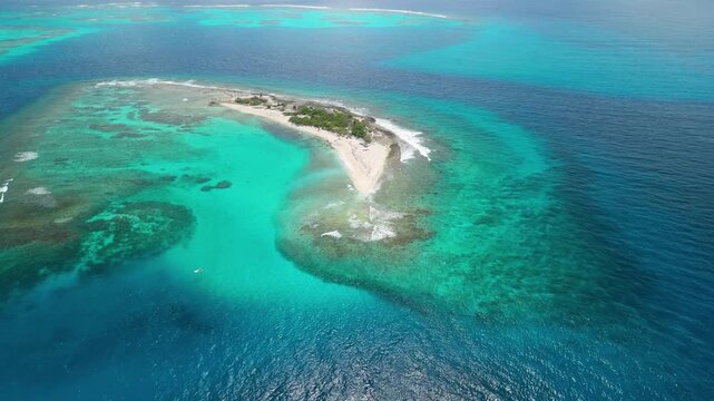 Wide aerial drone panorama reveals Petit Tabac island surrounded by vast coral reef patterns and turquoise Caribbean waters near Pirates of Caribbean filming site