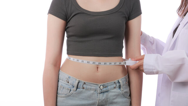 Doctor uses tape to measure slim waist of hopeful patient during modern medical weight loss consultation in clean clinic