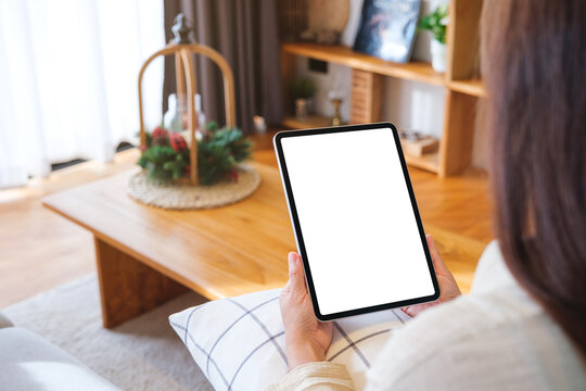 Mockup image of a woman holding tablet with blank desktop white screen at home