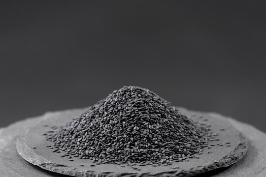 black sesame seeds, oilseed plant sesamum indicum on a black slate stone tray