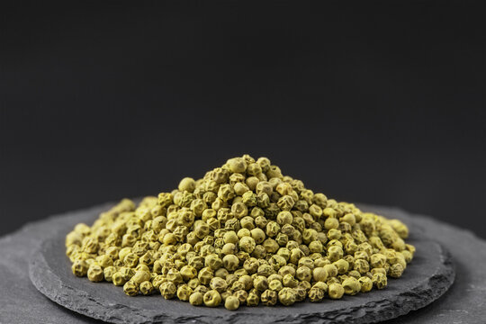 green peas dried unripe pepper plants Piper nigrum on a black slate stone tray