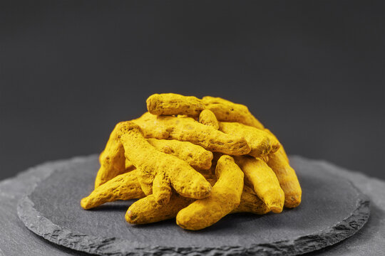 dried turmeric root or curcuma longa on a black slate stone tray