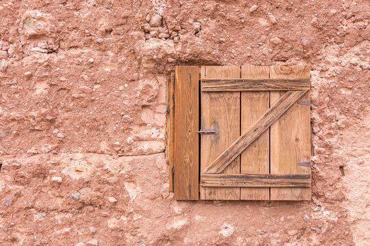 Old small closed wooden window on a stone wall with copy space