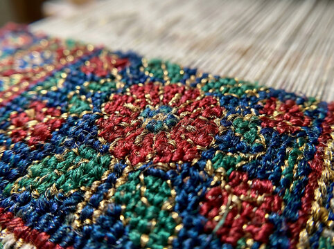 Close-up of a Kashmiri silk carpet with fine hand-knotted floral motifs and gold thread accents, showcasing traditional weaving craftsmanship from Srinagar, India