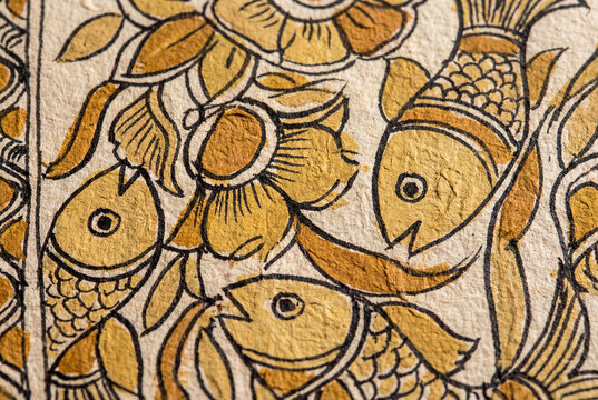 Close-up of Madhubani painting from Mithila, Bihar, featuring hand-drawn fish and floral motifs in ochre and gold tones on textured handmade paper