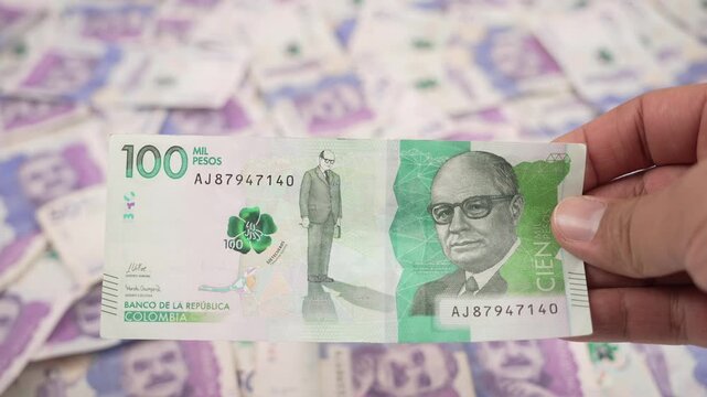 Holding colombian one hundred thousand pesos banknote