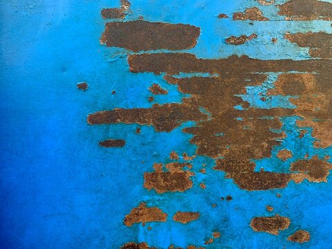 Rust and Blue Paint Texture: Close-up view of peeling blue paint revealing underlying rust, creating a unique abstract texture with a worn, distressed aesthetic.