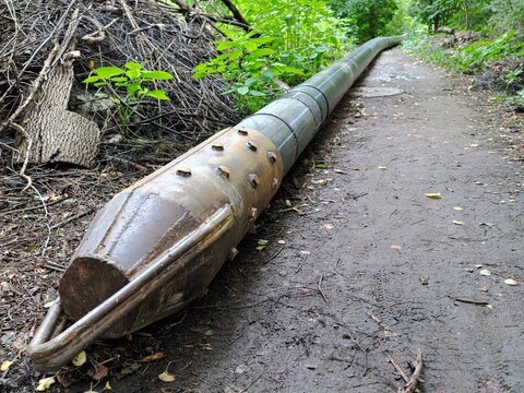 Heavy metal core barrel drill pipe resting on a muddy woodland trail