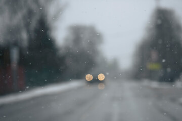 Dark background with car light bokeh and flying snowflakes. Winter elements, macro. © kulkann